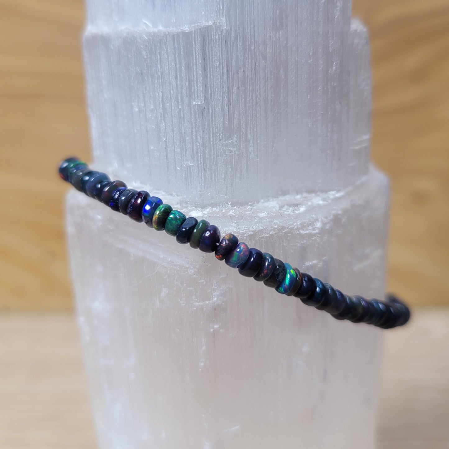 Close-up of a Black Opal Bracelet set in sterling silver, featuring vibrant, iridescent black opal stones with a captivating play of colors, elegantly mounted on a polished silver band