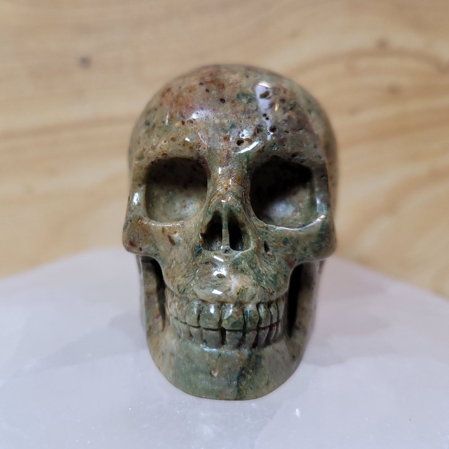  An intricately carved Agate Skull, featuring natural banding and vibrant colors of brown, cream, and gray, displayed against a soft, neutral background. This unique piece symbolizes emotional balance, wisdom, and introspection, making it an eye-catching decorative item.