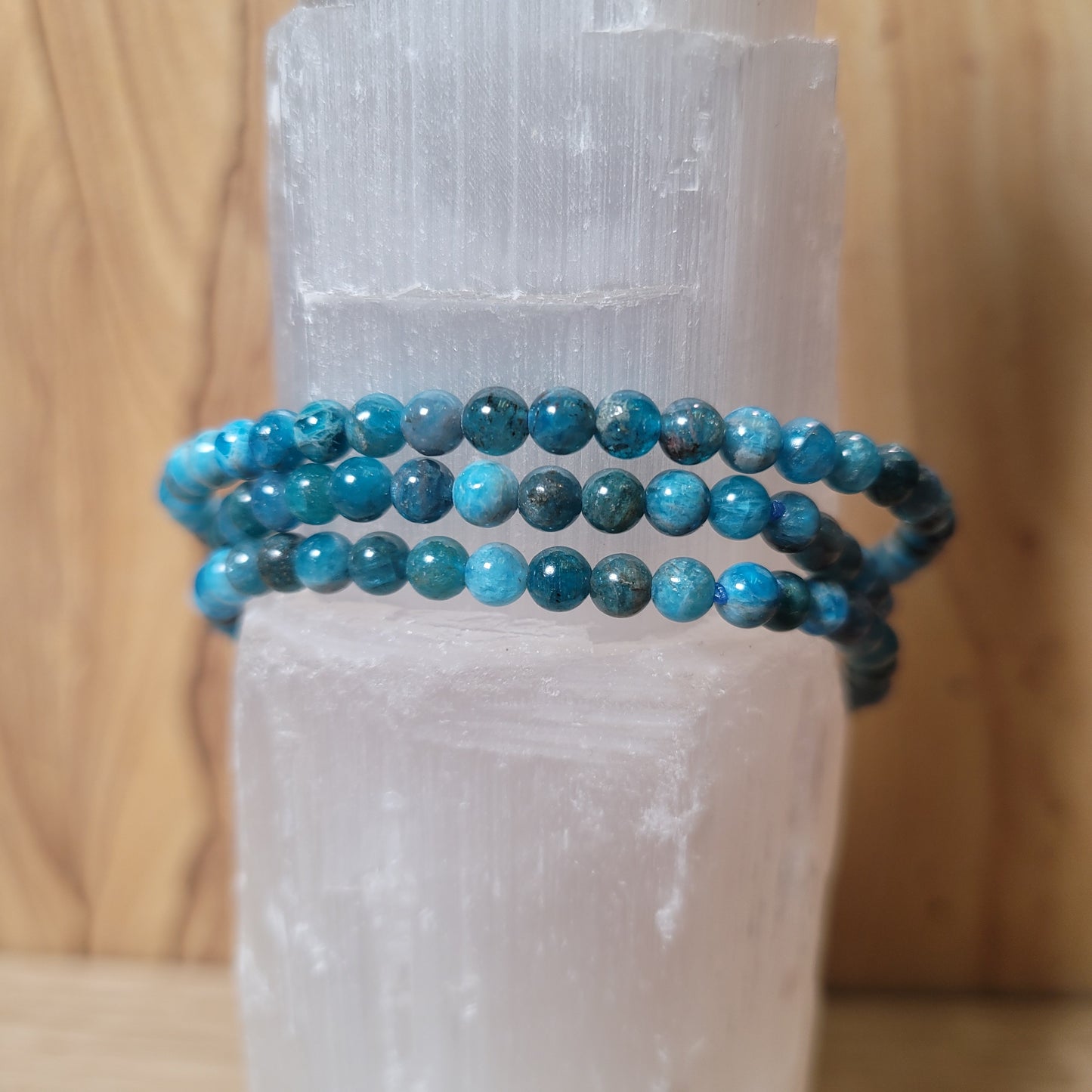 A delicate 4mm blue apatite bracelet featuring smooth, round beads in various shades of blue, displayed elegantly on a soft, neutral background. This charming piece showcases the natural beauty of blue apatite and its associated metaphysical properties, such as inspiration and communication.