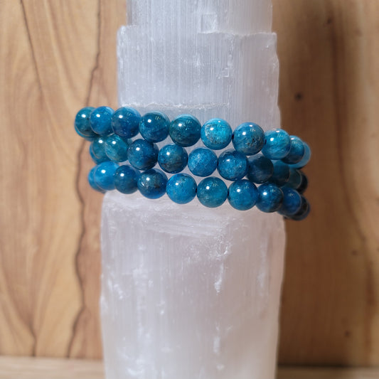 A delicate 7mm blue apatite bracelet featuring smooth, round beads in various shades of blue, displayed elegantly on a soft, neutral background. This charming piece showcases the natural beauty of blue apatite and its associated metaphysical properties, such as inspiration and communication.