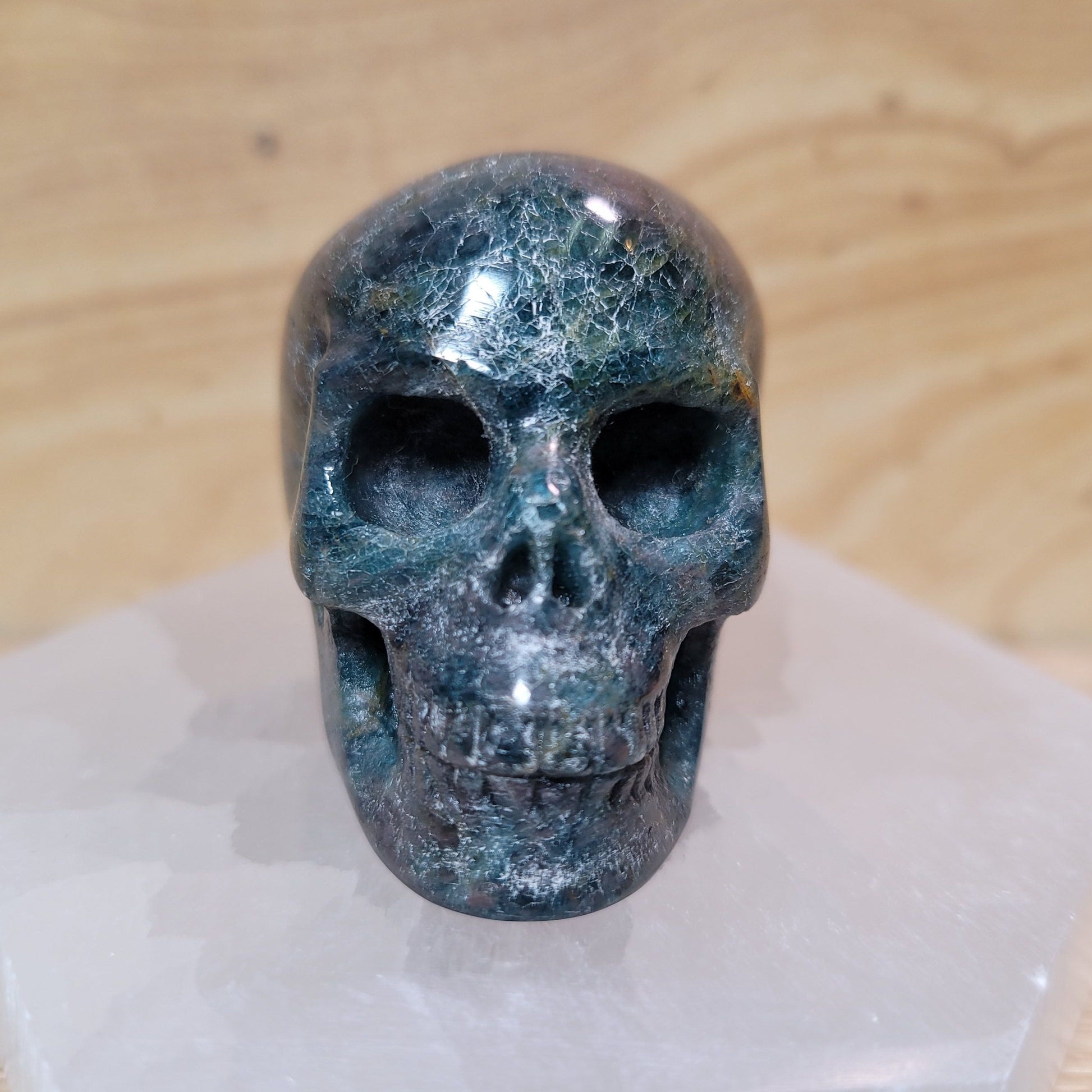 A beautifully crafted Blue Apatite Skull, showcasing its vibrant blue hues and intricate details, set against a soft, neutral background. This unique piece represents both artistic expression and the metaphysical properties of blue apatite, including mental clarity and enhanced communication.