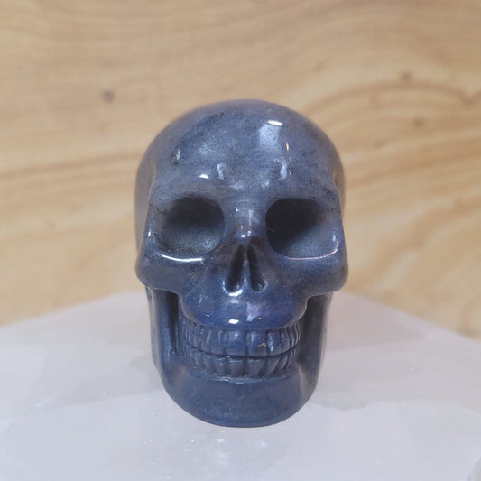 A beautifully hand-carved Blue Aventurine Skull, measuring 2 inches tall and weighing approximately 3.1 ounces, showcasing gentle blue tones and a shimmering effect, displayed against a soft, neutral background.