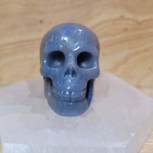 A beautifully crafted blue aventurine skull, featuring smooth surfaces and shimmering blue hues, displayed on a soft, neutral background. This unique piece symbolizes tranquility, emotional healing, and enhanced communication, making it an inspiring decorative item.