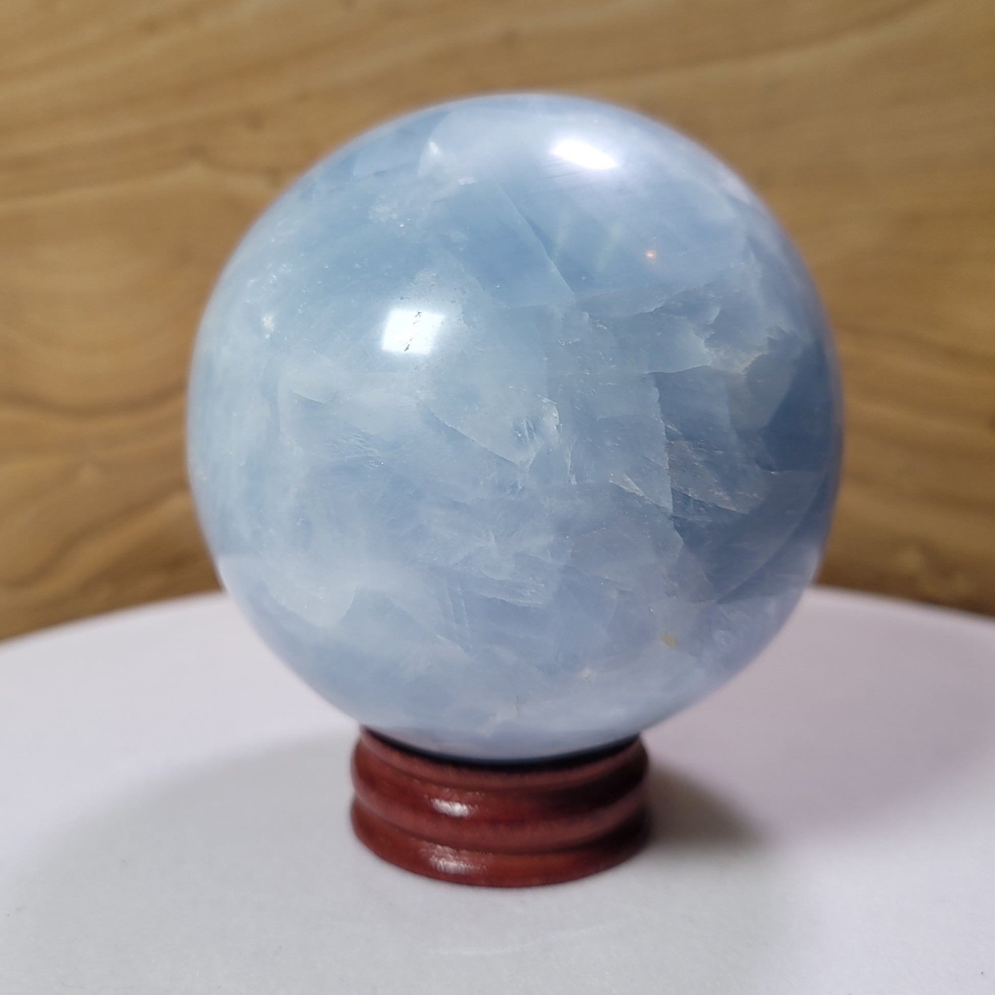 A beautifully polished Blue Calcite Sphere, showcasing gentle blue hues and natural variations, displayed against a soft, neutral background. This stunning piece symbolizes tranquility, emotional healing, and improved communication, making it an elegant decorative item.