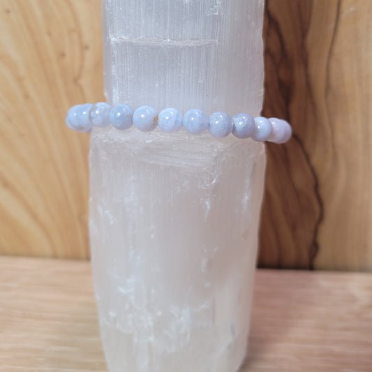 A delicate 6mm Blue Lace Agate Bracelet featuring soft blue beads with intricate lace-like patterns, displayed against a soft, neutral background. This elegant piece symbolizes calmness, emotional healing, and effective communication, making it a beautiful accessory.