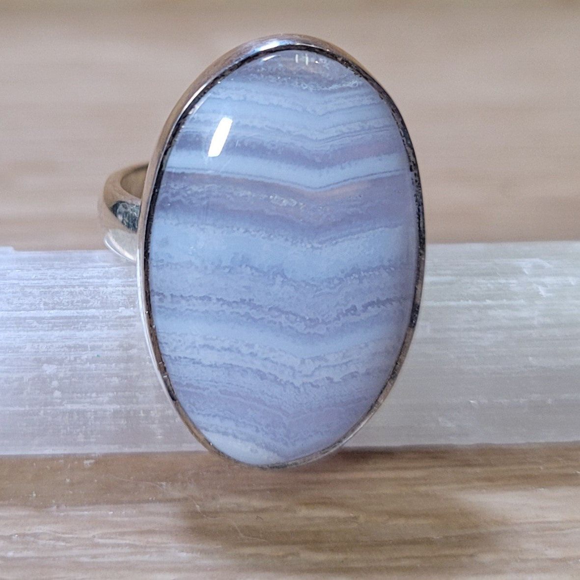 An elegant Blue Lace Agate Adjustable Ring featuring a captivating gemstone with delicate lace-like patterns in soft blue and white, displayed against a soft, neutral background. This unique piece symbolizes tranquility and emotional balance, making it a stunning accessory.