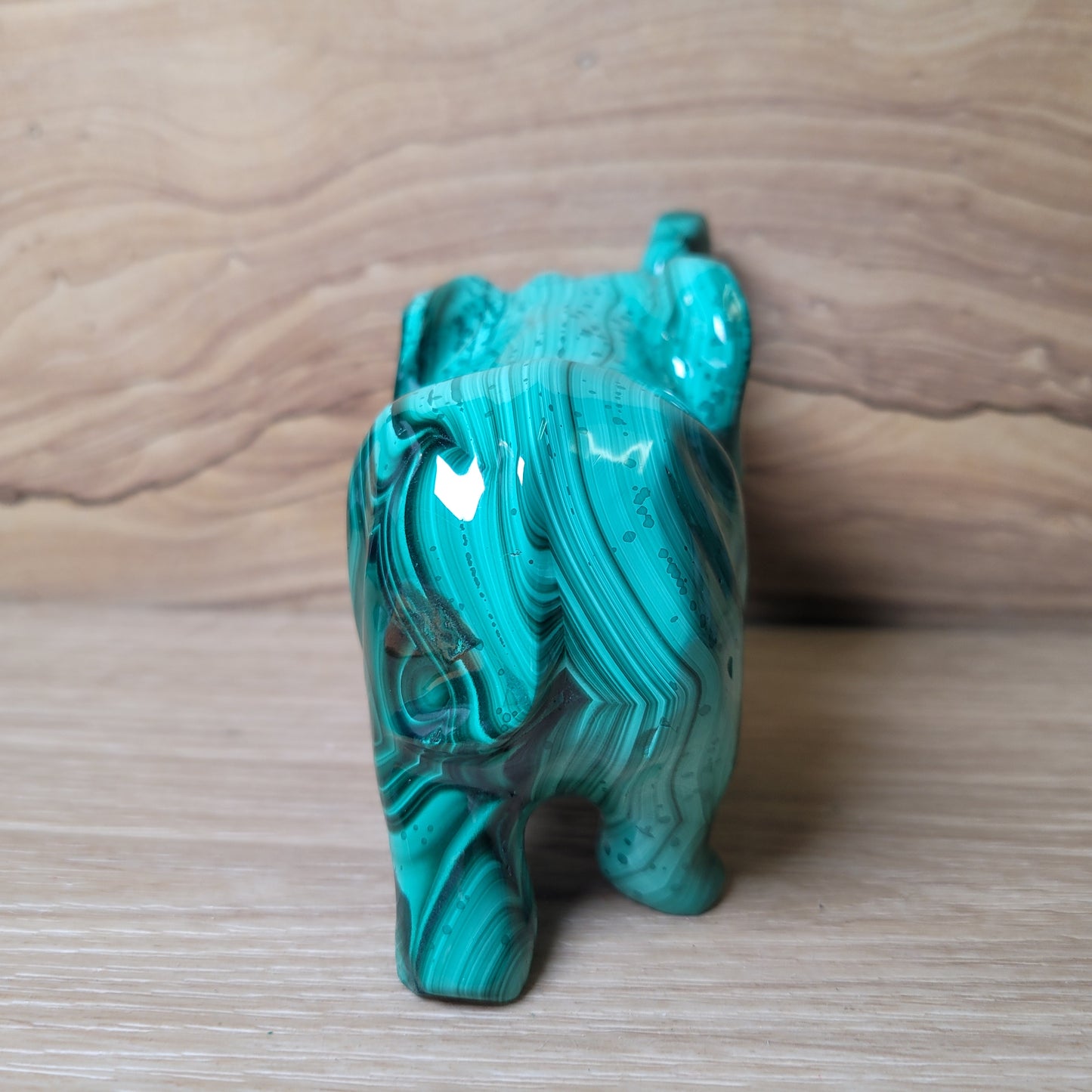 Green Malachite stone carving of a elephant on a wooden surface