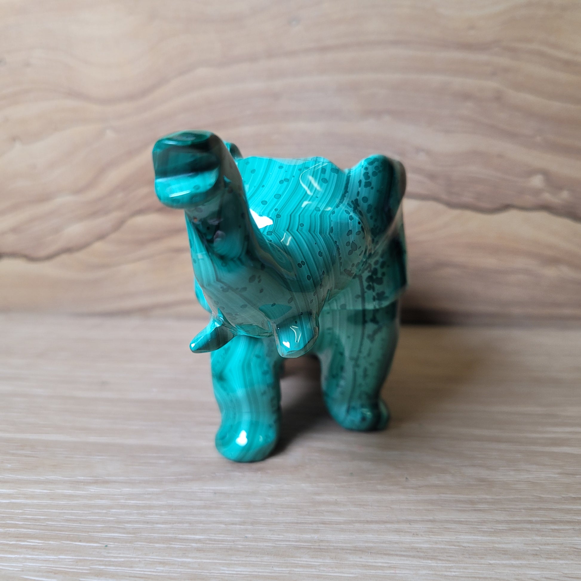 Green Malachite elephant carving on a wooden surface