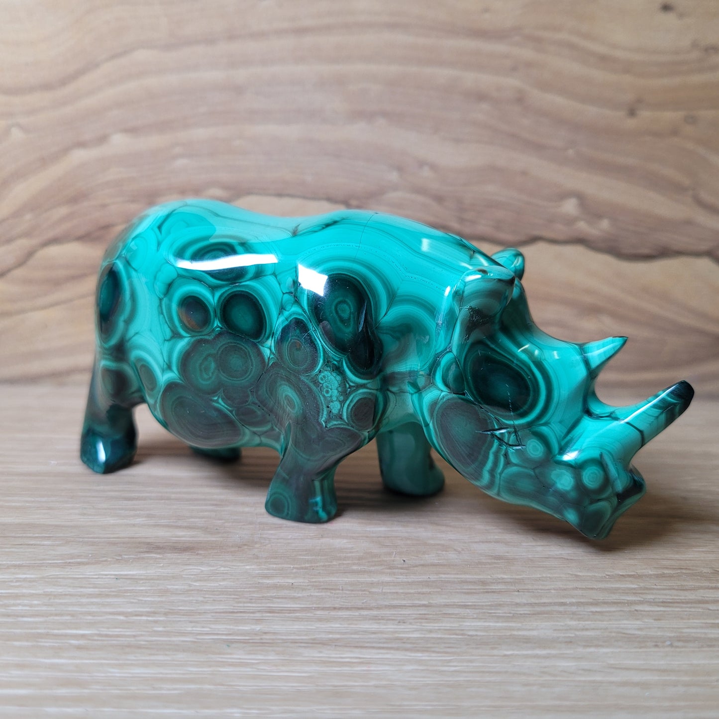 Green Malachite rhinoceros figurine on a wooden surface