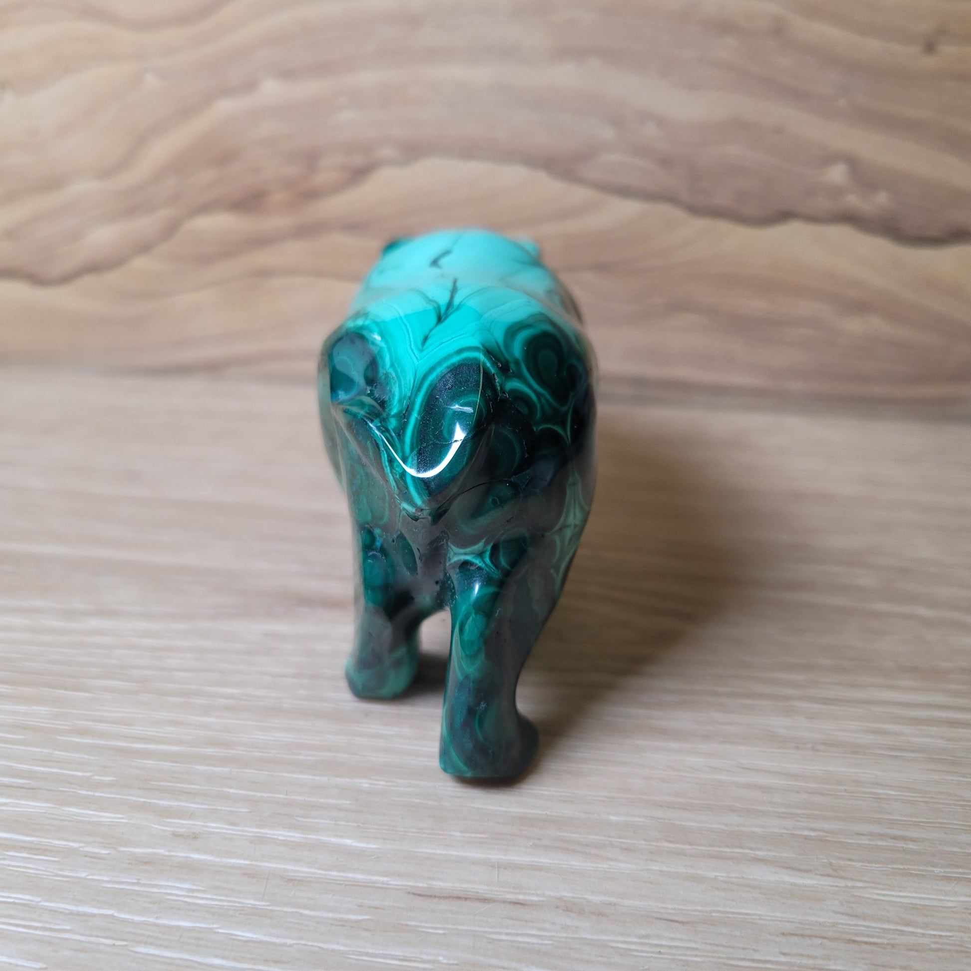 Green Malachite elephant carving on a wooden surface