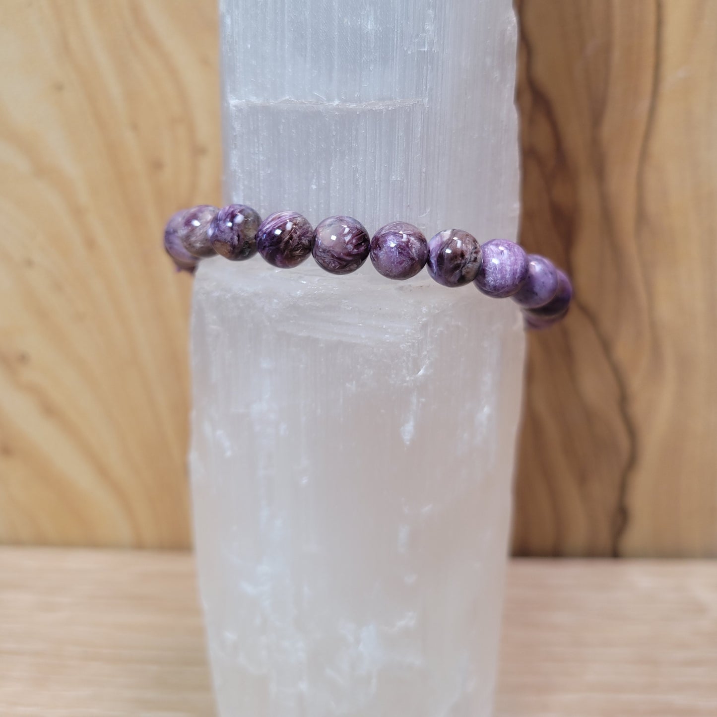 A bracelet made of 7.5mm charoite beads, showcasing the gemstone's rich purple hues and unique swirling patterns. The beads are strung together on a flexible cord, creating a stylish accessory that highlights the natural beauty of the charoite stone. The bracelet is displayed on a neutral background to emphasize its color and texture.