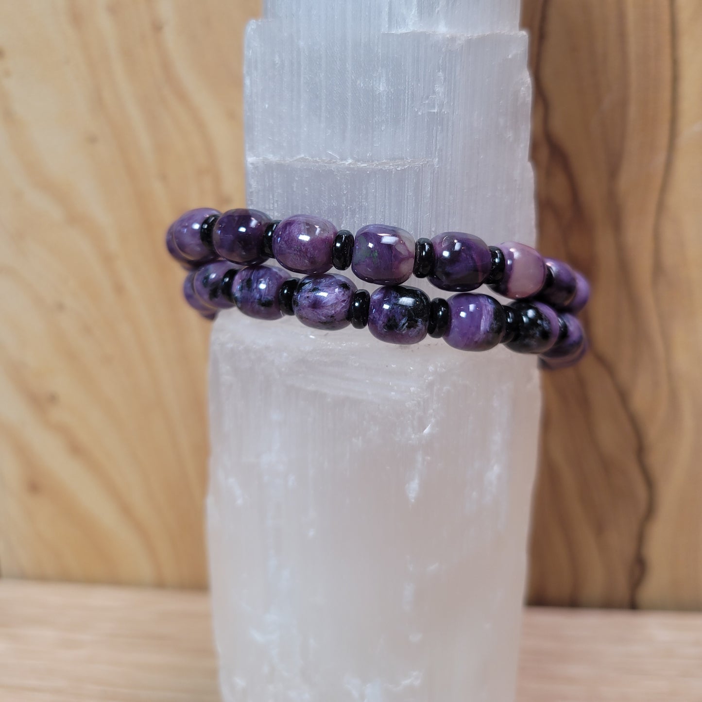 A bracelet featuring 7.5mm beads of charoite and onyx, alternating between the rich purple charoite with its swirling patterns and the sleek, glossy black onyx. The beads are strung together on a flexible cord, creating a balanced and elegant accessory. The bracelet is displayed against a neutral background to highlight the contrasting colors and textures of the beads