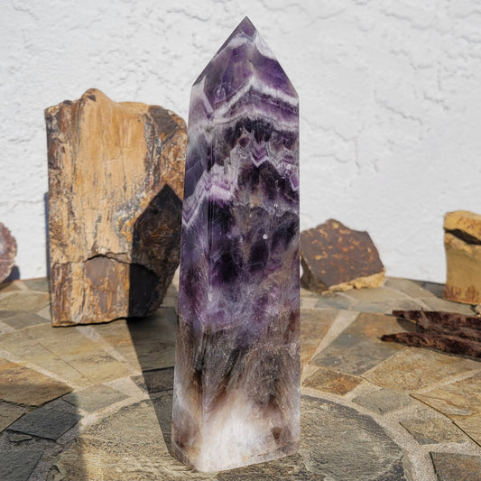 Dream Amethyst Tower – Stunning amethyst crystal tower featuring deep purple hues and unique inclusions. This beautiful piece is renowned for enhancing dreams, stimulating intuition, and promoting spiritual growth. Ideal for meditation, emotional healing, and as a protective energy tool, it adds elegance and powerful metaphysical properties to any space