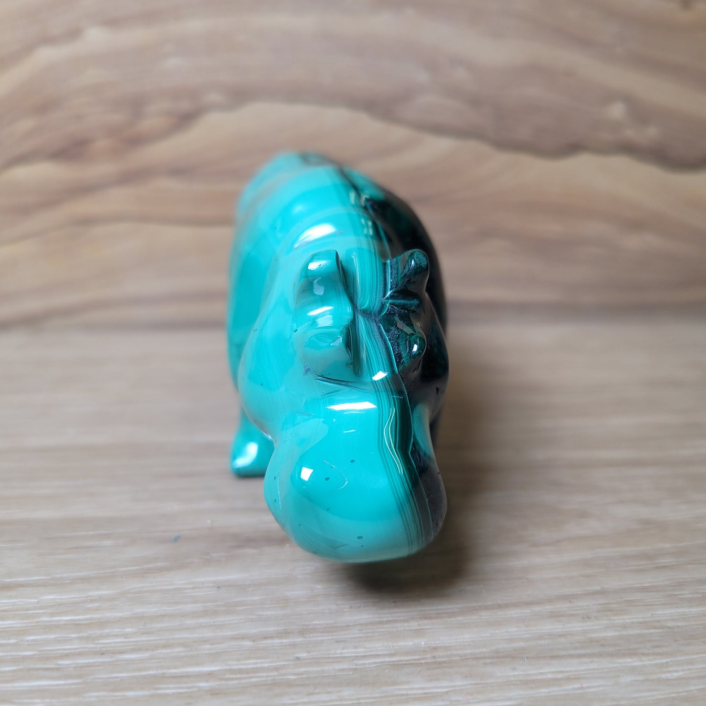 Green Malachite rhinoceros figurine on a wooden surface