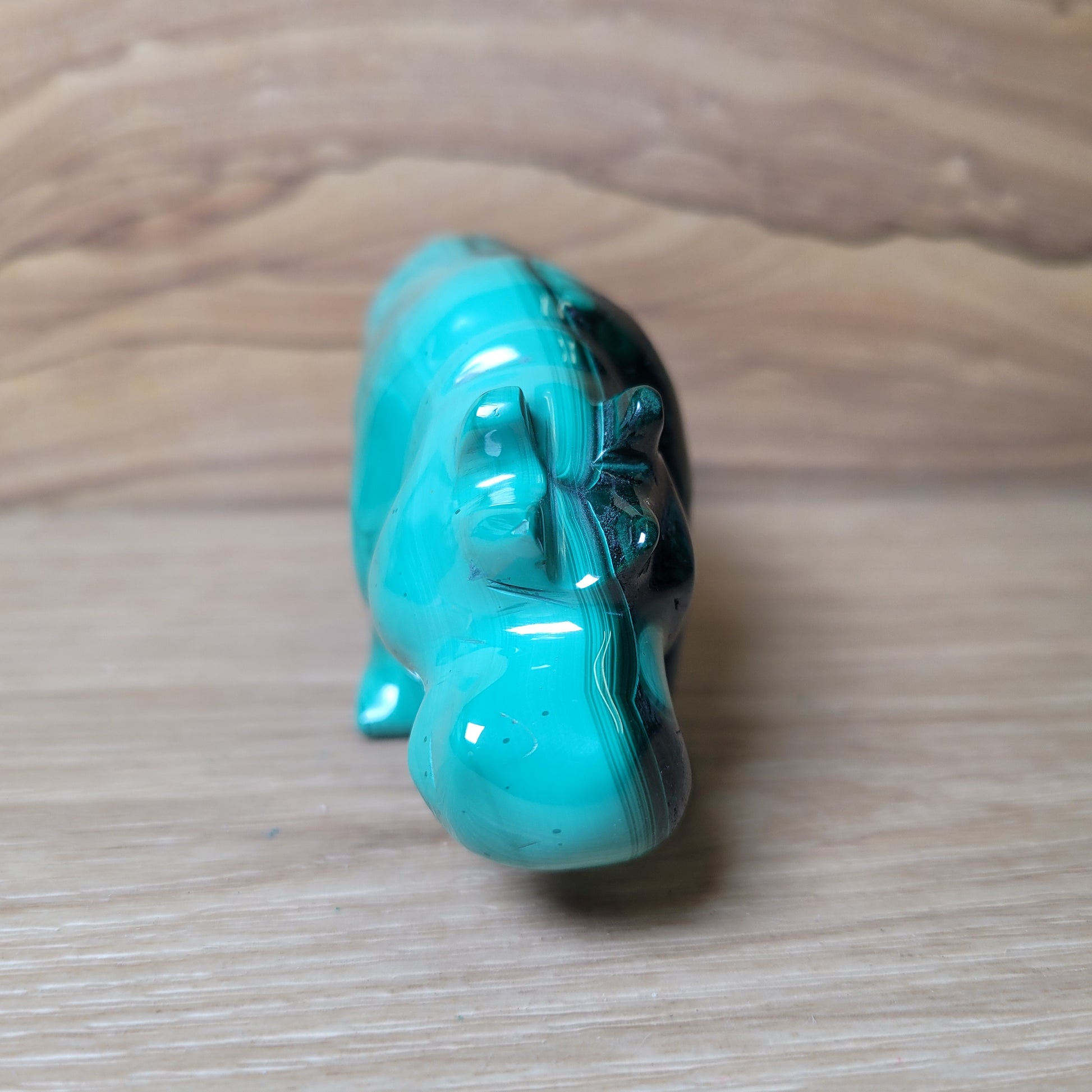 Green Malachite rhinoceros figurine on a wooden surface
