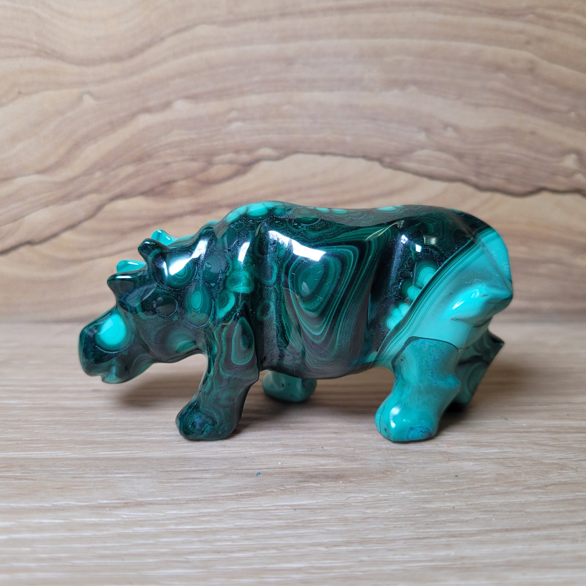 Green malachite Hippopotamus figurine on a wooden surface