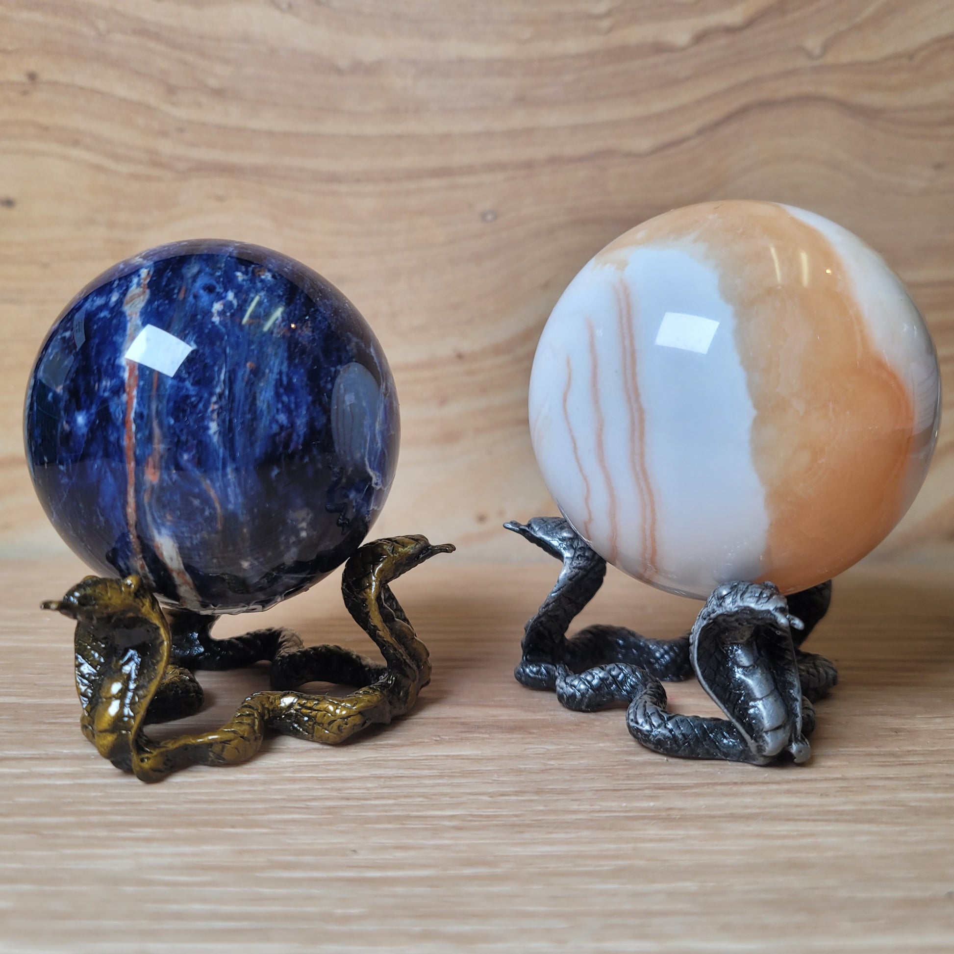 Two decorative spheres with snake stands on a wooden surface