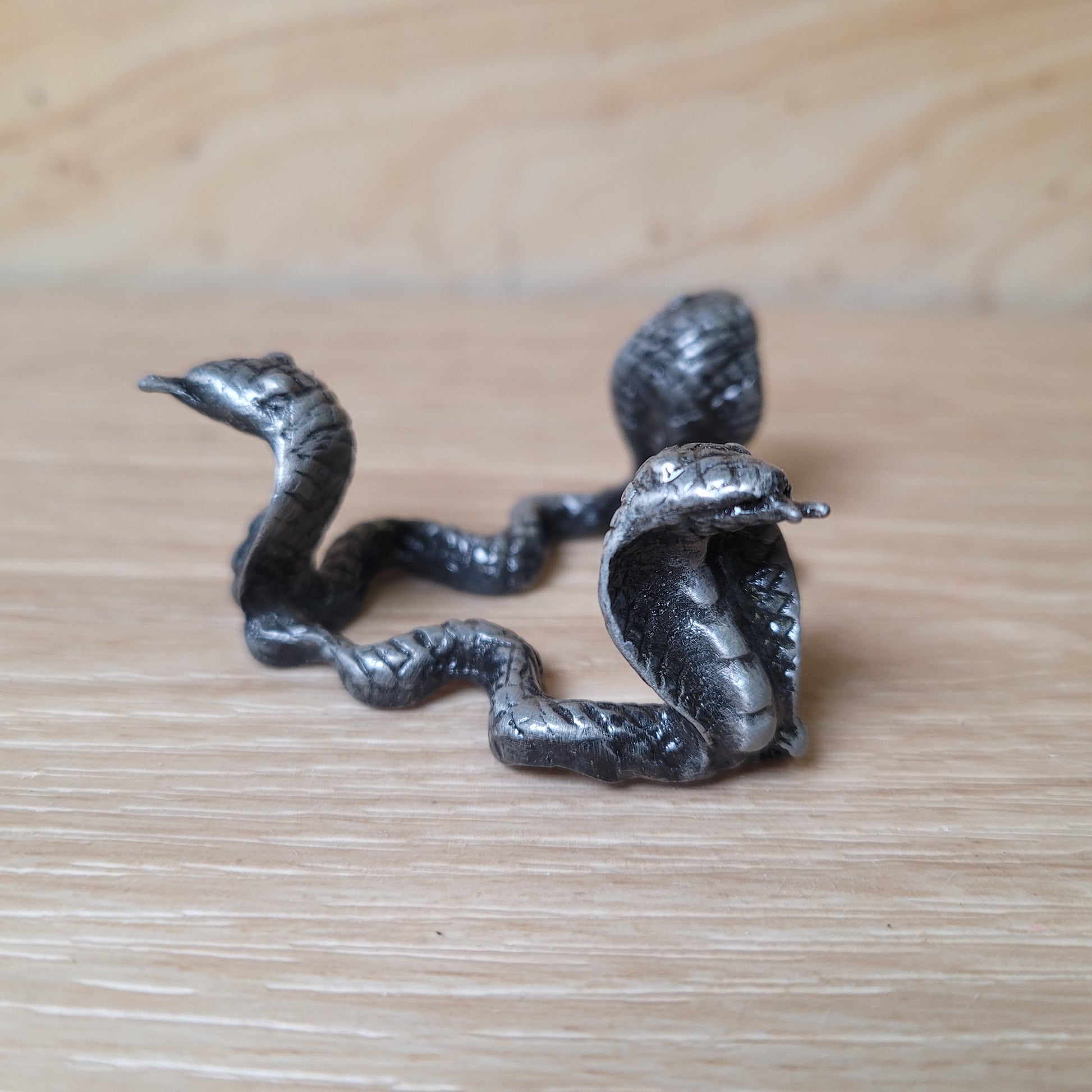 Metallic snake-shaped object on a wooden surface