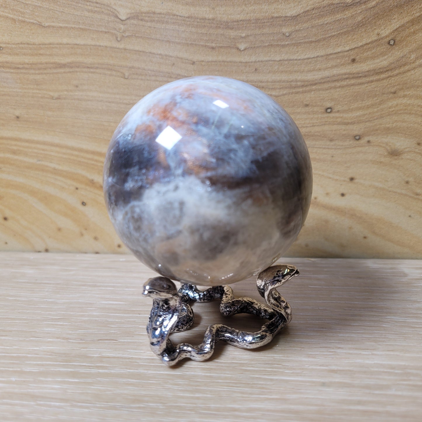 Decorative sphere with a silver snake on a wooden surface